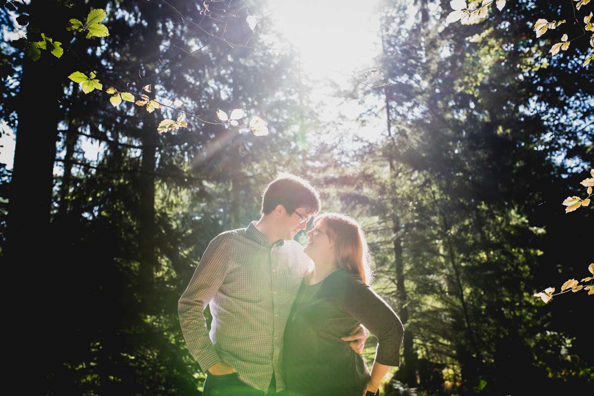 couple kissing in the forest with bright back lighting