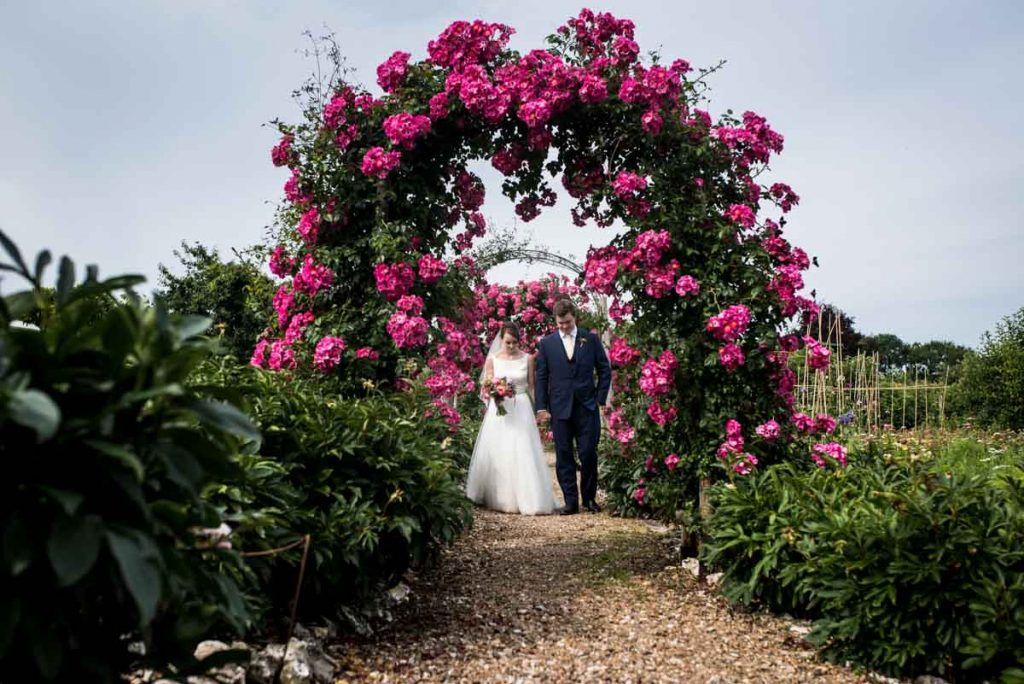 couple in pink flower arch at Houghton Lodge gardens