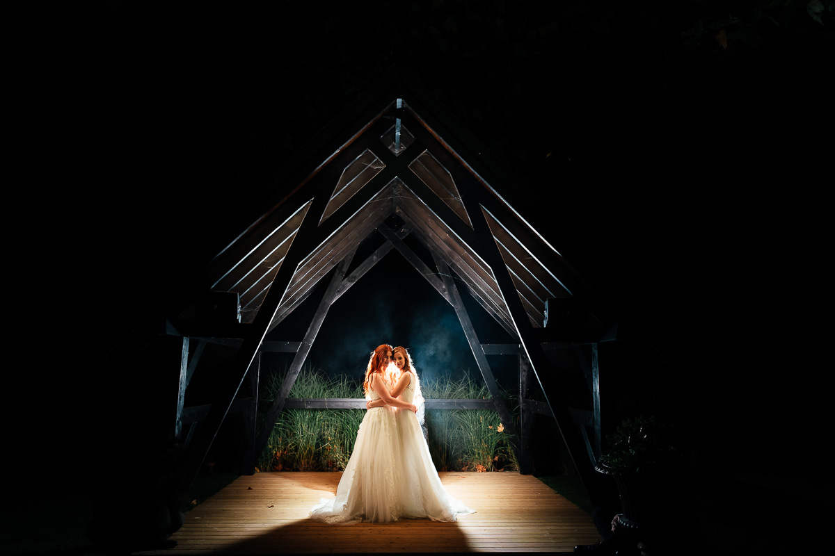 Two brides backlit in a wooden arch