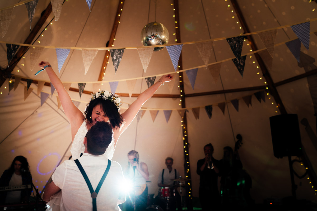 Bride dancing with husband at festival with arms in the air