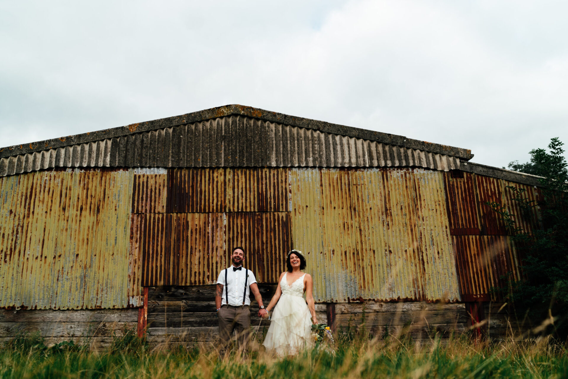 wedding couple in front of rusty barn